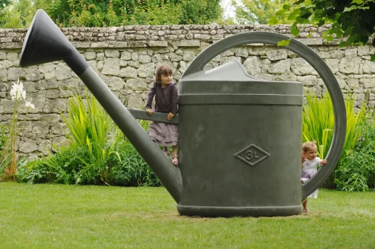 Enfants jouant dans un arrosoir géant dans le parc du chateau