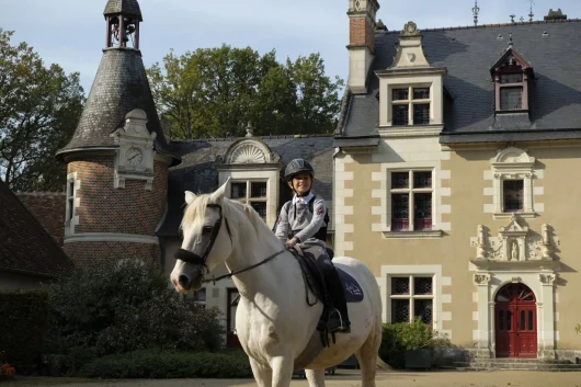 Enfant sur un cheval blanc dans la cour du château