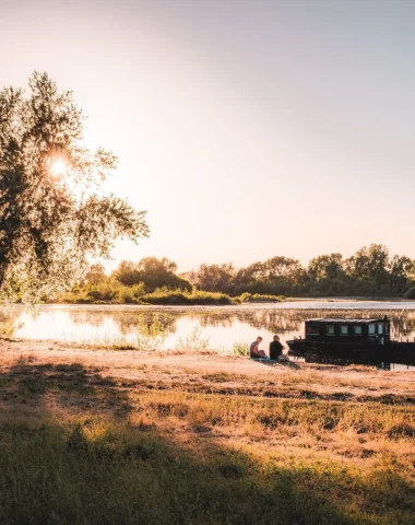 Couple assis sur les bords de Loire, un bateau amarré devant eux